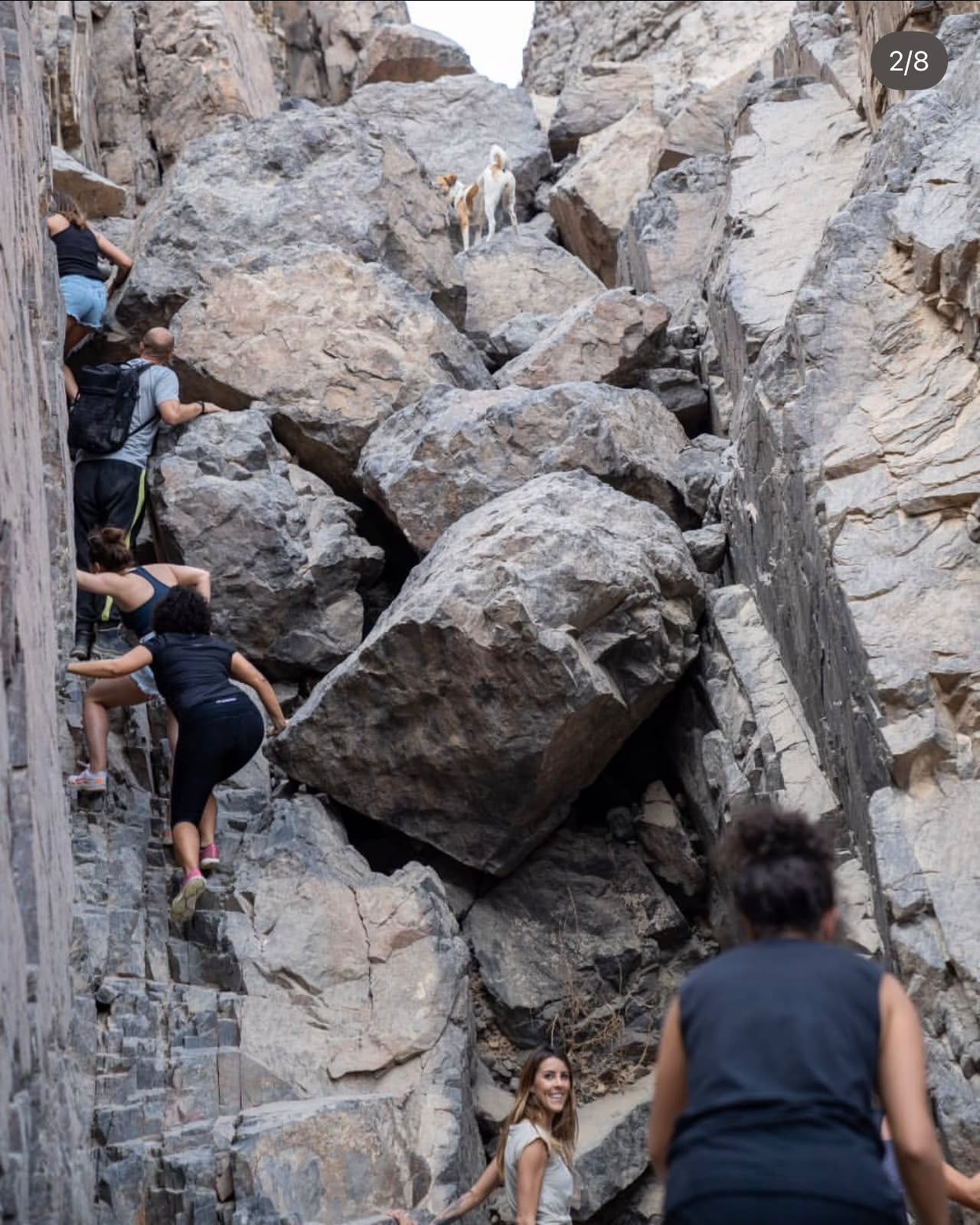 Four hikers climbing together through a rocky mountain passage